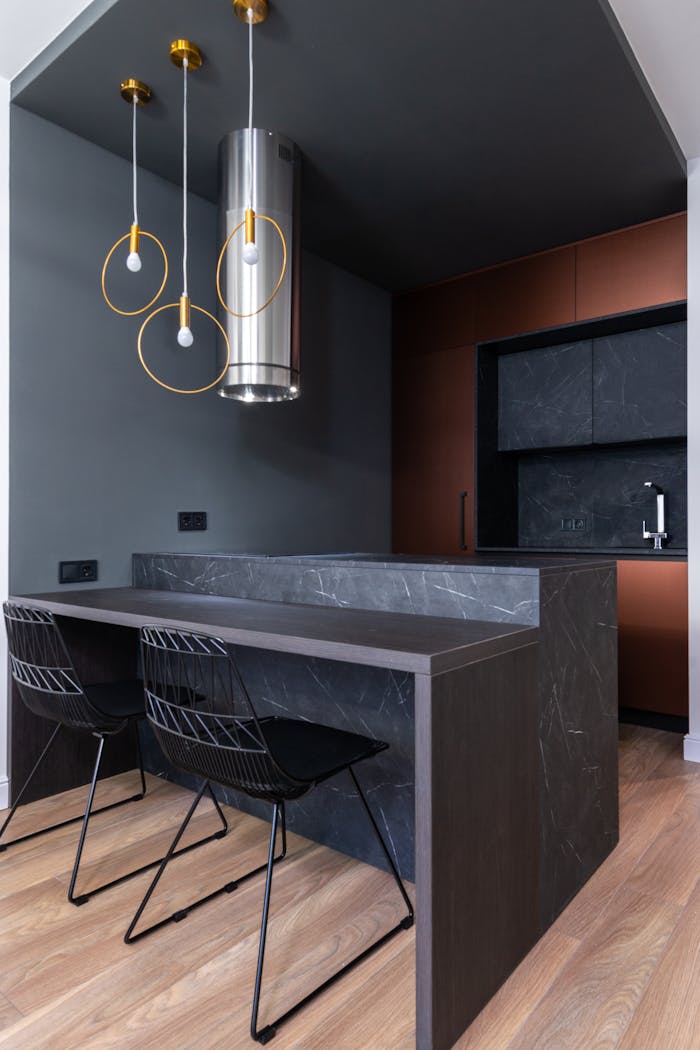 Contemporary kitchen with stylish pendant lights, marble countertop, and minimalist chairs.